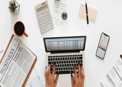 Top view of a workspace with laptop, business documents, calculator, and coffee, representing productivity and business analysis